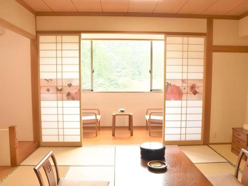 a japanese room with a window and a table and chairs at Hotel Hikyounoyu in Miyoshi