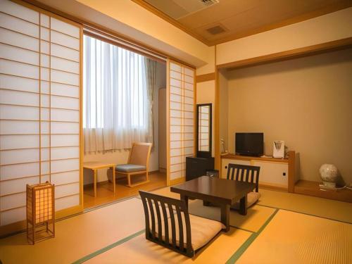 a living room with a table and chairs and a room with a tv at Hotel Hikyounoyu in Miyoshi