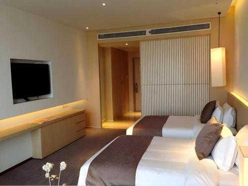 a hotel room with a large bed and a flat screen tv at Xian Elegant Oriental Hotel in Xi'an