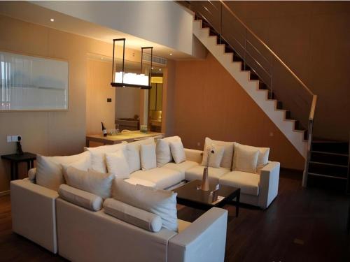 a living room with a white couch and a staircase at Xian Elegant Oriental Hotel in Xi'an