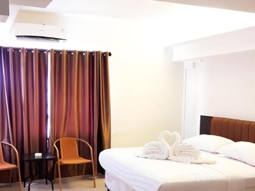 Una habitación de hotel con dos camas y una mesa y sillas. en Karimun City Hotel, en Tanjung Balai Karimun