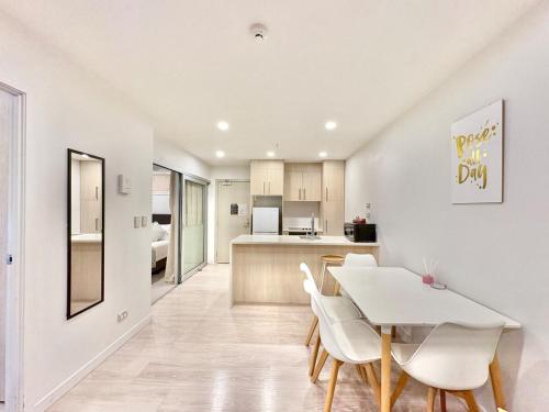 a kitchen and dining room with a white table and chairs at High-Floor 2BR Apartment Near Sky Tower Pool Gym in Auckland