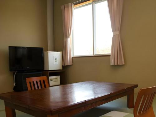 a dining room table with a television and a window at Nest West Garden Tosa Hotel in Shimanto