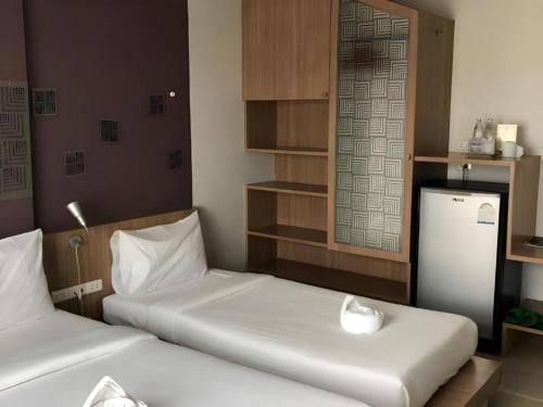 a room with two beds and a refrigerator at Tonkok Hotel in Chiang Rai