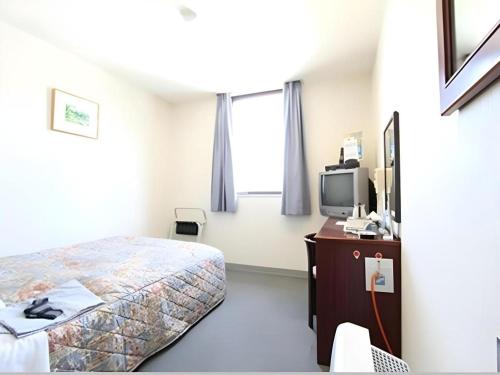 a bedroom with a bed and a desk and a tv at Hotel Matsuya in Shimanto