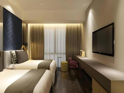 a hotel room with two beds and a flat screen tv at Metropolo Hotel Qingdao Wusi Square Xiaomaidao in Qingdao