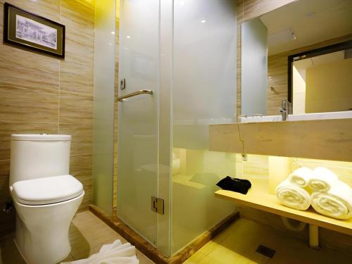 a bathroom with a toilet and a glass shower at Metropolo Hotel Qingdao Wusi Square Xiaomaidao in Qingdao