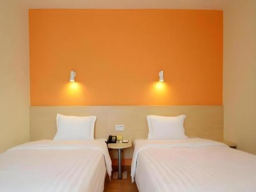 two beds sitting next to each other in a room at 7 Days Inn Luoyang Wangcheng Park Metro Station in Luoyang