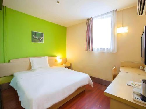 a bedroom with a white bed and a green wall at 7 Days Inn Nanjing Gaochun Metro Station in Gaochun