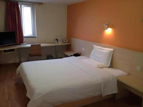 a bedroom with a large white bed and a desk at 7 Days Inn Nanjing Gaochun Metro Station in Gaochun