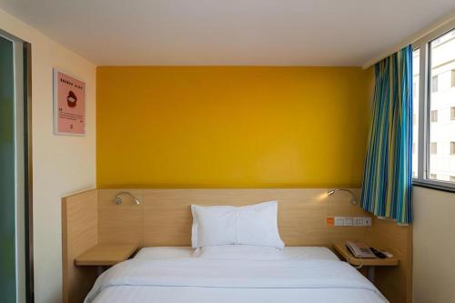 a bedroom with a bed with a yellow wall at 7 Days Inn Chengdu North Railway Metro Station in Chengdu