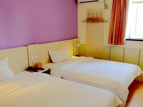 two beds in a room with purple and purple walls at 7 Days Inn Nanjing Gaochun Metro Station in Gaochun