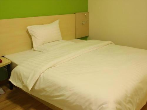 a white bed in a room with a green wall at 7 Days Inn Chengdu North Railway Metro Station in Chengdu