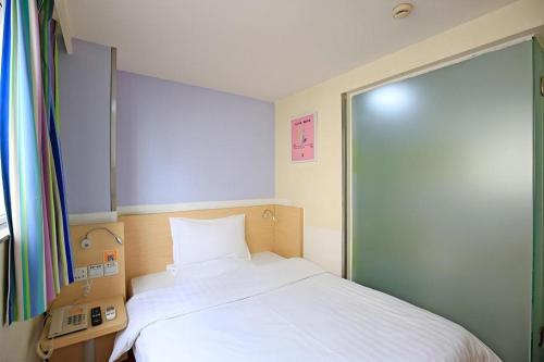 a small bedroom with a bed and a phone at 7 Days Inn Chengdu North Railway Metro Station in Chengdu