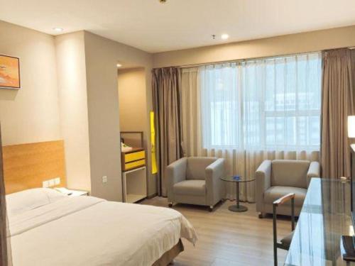 a hotel room with a bed and two chairs at Catic Hotel--Adjacent Buliding in Zhuhai