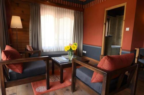 a living room with two chairs and a table with flowers at Hotel Valley Thimphu in Thimphu
