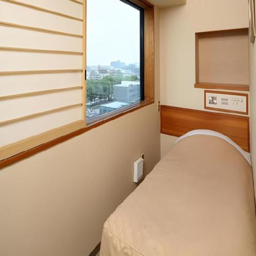 a hospital room with a bed and a window at Hotel Grand Shinonome in Tsukuba