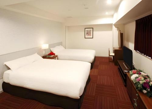 a hotel room with two beds and flowers in it at Hotel Grand Shinonome in Tsukuba