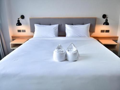 two white shoes sitting on top of a bed at @Sleep in Nakhon Pathom