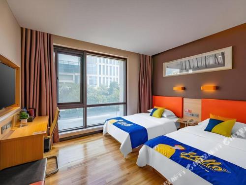 ein Hotelzimmer mit zwei Betten und einem Flachbildfernseher in der Unterkunft 7Days Premium Nanjing Olympic Sports International Exhibition Center in Nanjing