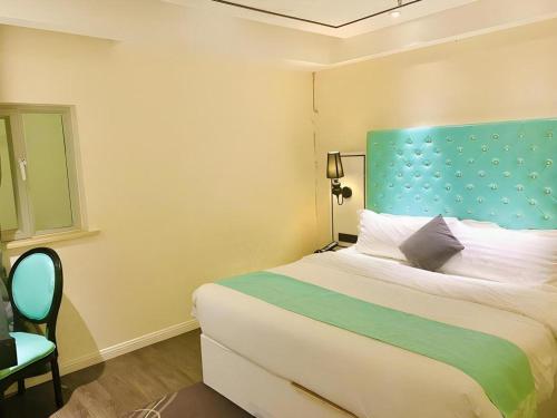 a bedroom with a large bed with a blue headboard at Xana Lite Korla Xiangli Avenue Food Street in Korla
