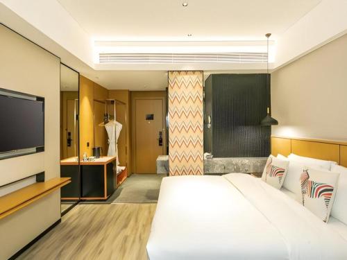 a bedroom with a large white bed and a flat screen tv at SOFIS POP HOTEL in Fuzhou