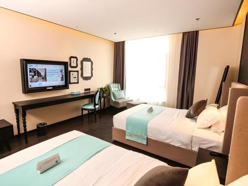 a hotel room with two beds and a television at Xana Hotelle·Ji'nan Hi-tech Zone Century Avenue Tangye in Jinan