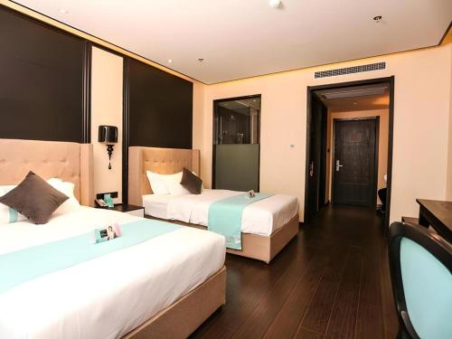 a hotel room with two beds and a mirror at Xana Hotelle·Ji'nan Hi-tech Zone Century Avenue Tangye in Jinan