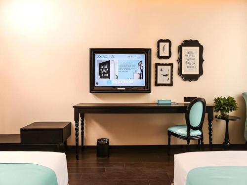 a room with a tv and a desk with a chair at Xana Hotelle·Ji'nan Hi-tech Zone Century Avenue Tangye in Jinan