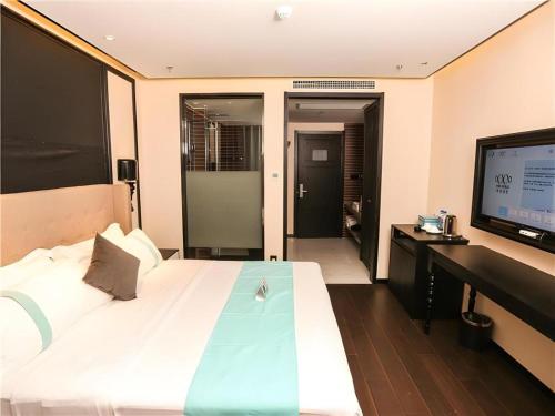 a bedroom with a large bed and a flat screen tv at Xana Hotelle·Ji'nan Hi-tech Zone Century Avenue Tangye in Jinan