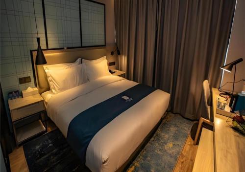 a bedroom with a large bed in a hotel room at Echarm Hotel Zibo Gaoqing Zhongcheng Inernational in Zibo