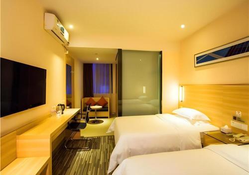 a hotel room with two beds and a television at JTOUR Inn Wuzhou Arcade City Sanzongfu in Wuzhou