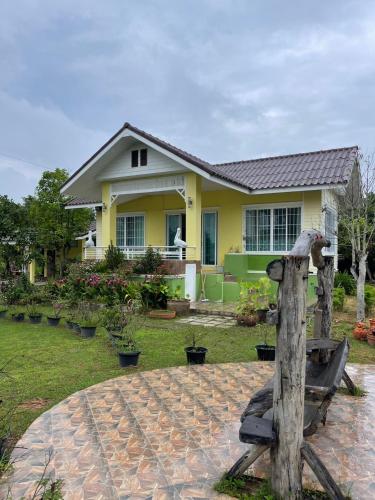 a yellow house with a bird statue in front of it at Ray's in Ban Phae Buak Ha