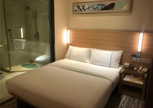 a bedroom with a bed and a glass shower at City Comfort Inn Wuhan Dongwu Avenue Light Rail Station in Wuhan
