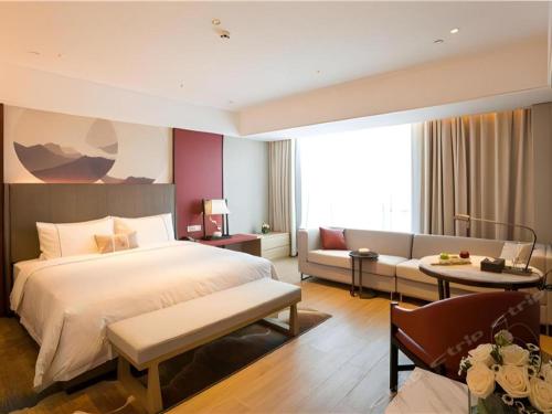 a hotel room with a bed and a couch at Echeng Hotel Sanming City Government RT-Mart in Sanming