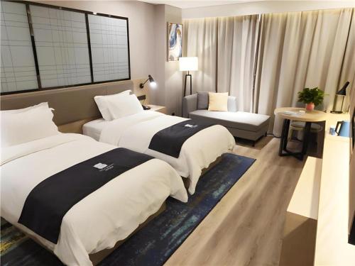 a hotel room with two beds and a couch at Echarm Hotel Yingshang High-speed Railway Station Wuzhou Wanhui Plaza in Fuyang