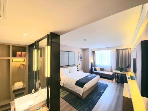 a hotel room with a bed and a bathroom at Echarm Hotel Yingshang High-speed Railway Station Wuzhou Wanhui Plaza in Fuyang