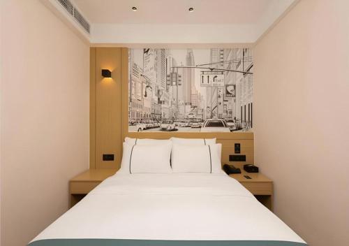 a bedroom with a white bed and a picture of a city at City Comfort Inn Guangzhou Southern Hospital Tonghe Metro Station in Guangzhou