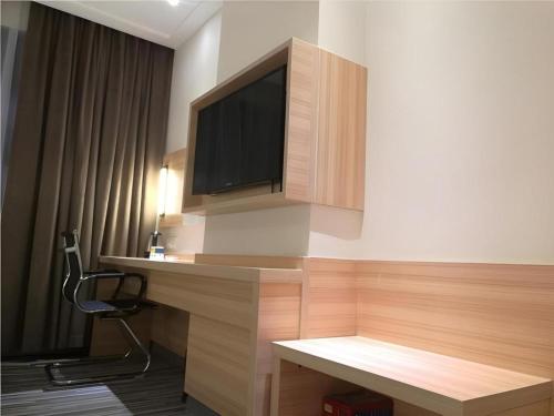 a room with a desk with a tv on a wall at City Comfort Inn Shenzhen Shiyan Science and Technology Park in Shenzhen