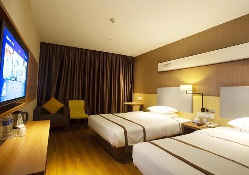 a hotel room with two beds and a flat screen tv at Jtour Inn Huanggang Wuxue City Square in Wuxue