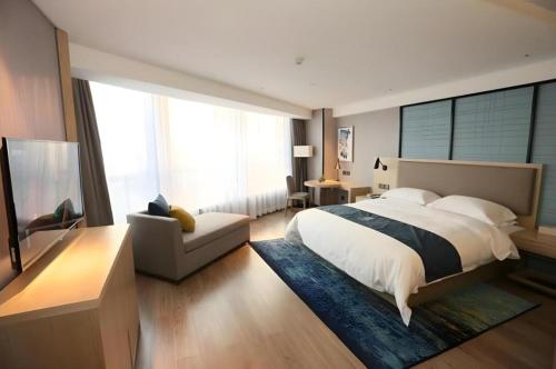 a bedroom with a bed and a couch and a television at Echarm Hotel Chengdu Pidu Comprehensive Bonded Zone BOE in Chengdu