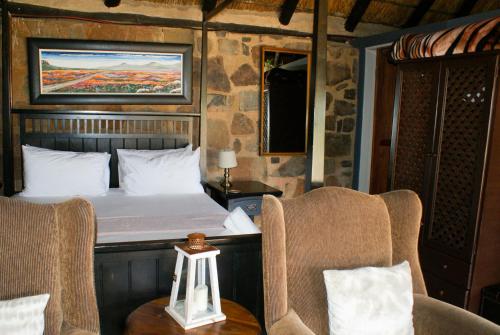 a bedroom with a bed and two chairs and a table at Riverman Cabin Country Lodge - Tonteldoos in Tonteldoos