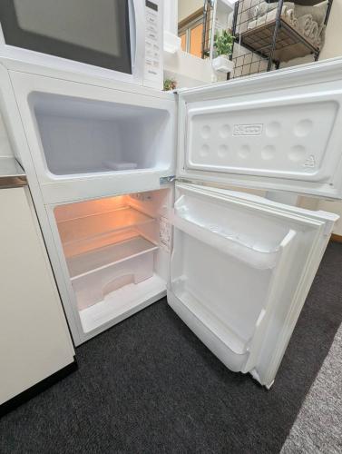 an empty refrigerator with its door open in a kitchen at Doggo Inn ベッド4台でゆったり宿泊 新潟駅徒歩7分 コンビニ徒歩1分 ペットと泊まれる宿 in Niigata