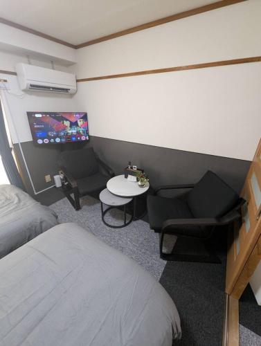 a bedroom with a bed and a table and a tv at Doggo Inn ベッド4台でゆったり宿泊 新潟駅徒歩7分 コンビニ徒歩1分 ペットと泊まれる宿 in Niigata