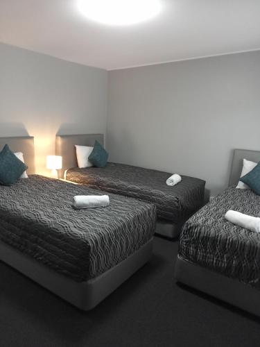 a hotel room with two beds with blue pillows at Solomon Inn Motel Figtree in Wollongong