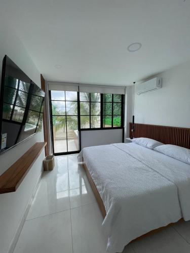 ein weißes Schlafzimmer mit großem Bett und Fenstern in der Unterkunft GLAMSUITE Montañita in Montañita
