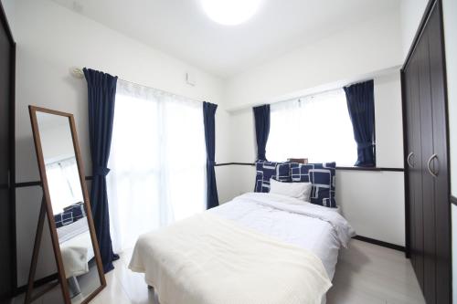 a bedroom with a bed and a mirror at Exsaison OKINAWA in Itoman