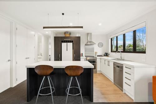 a kitchen with a island with two bar stools at Vista Haven - Bannockburn Holiday Home in Bannockburn