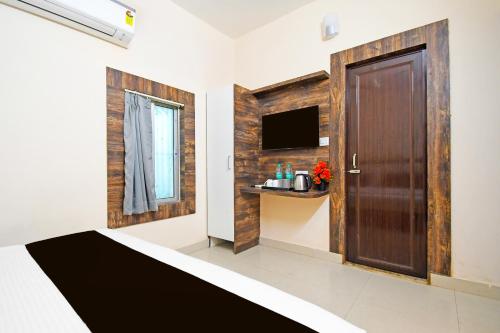 a room with a wooden door and a television at Super Collection O Gandhi Ghat Formerly Sai Resorts in Puri