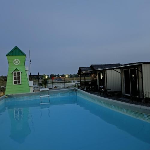 a large swimming pool with a clock tower next to a building at Chinta Chinta Cottage kabin 1 in Arau